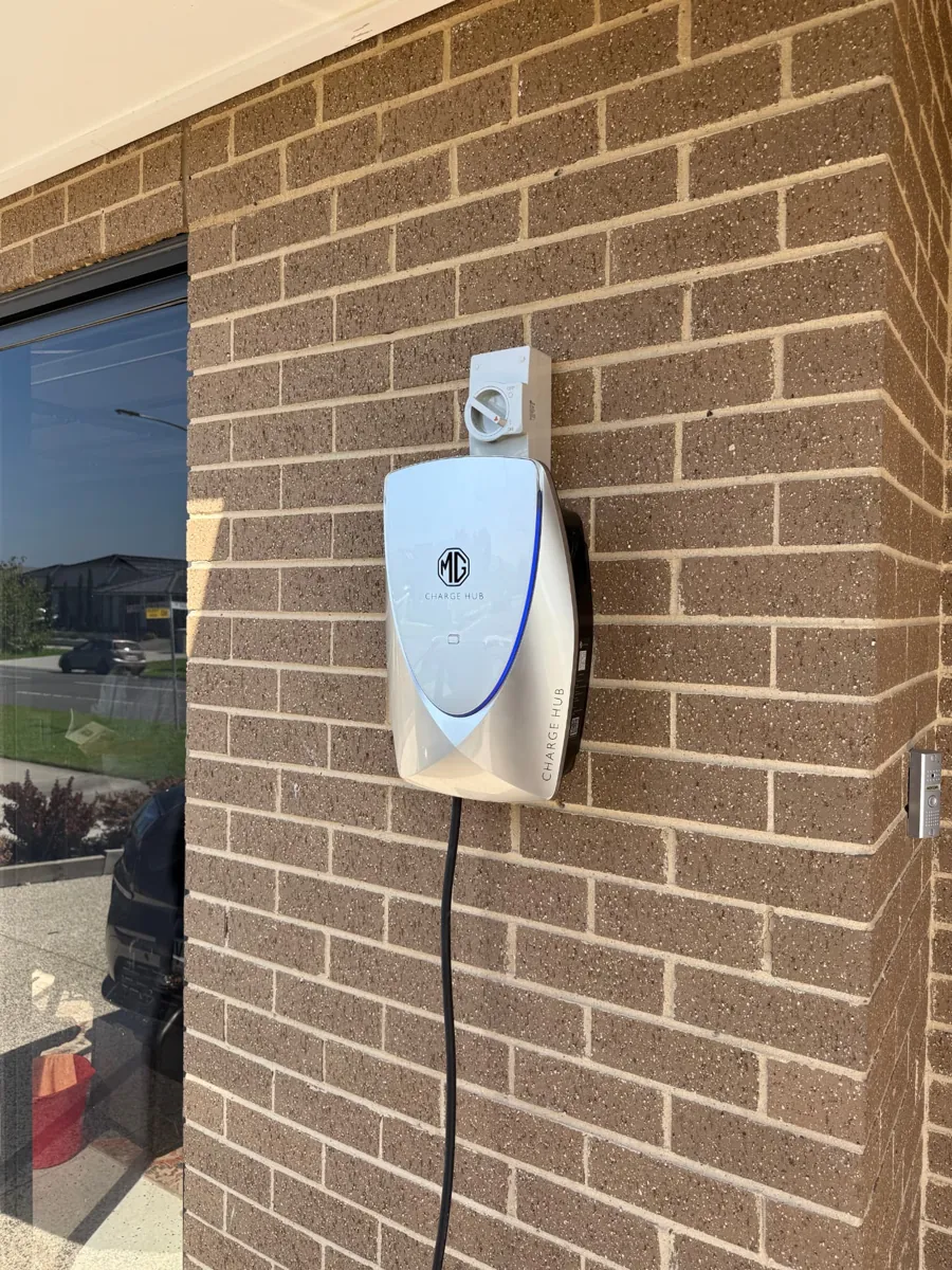 MG Charge Hub EV charger installed with isolator switch on a brick wall