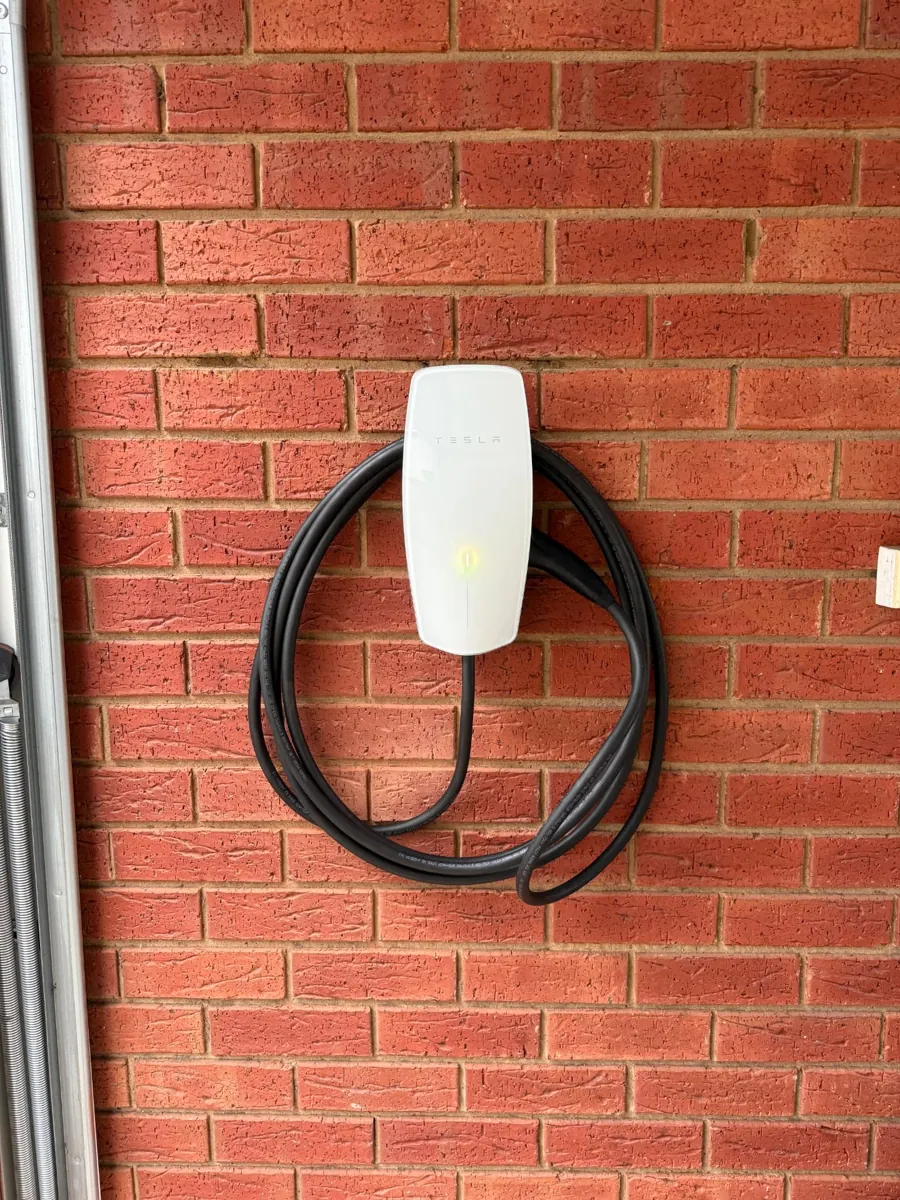 Tesla Wall Connector installed on a red brick garage wall