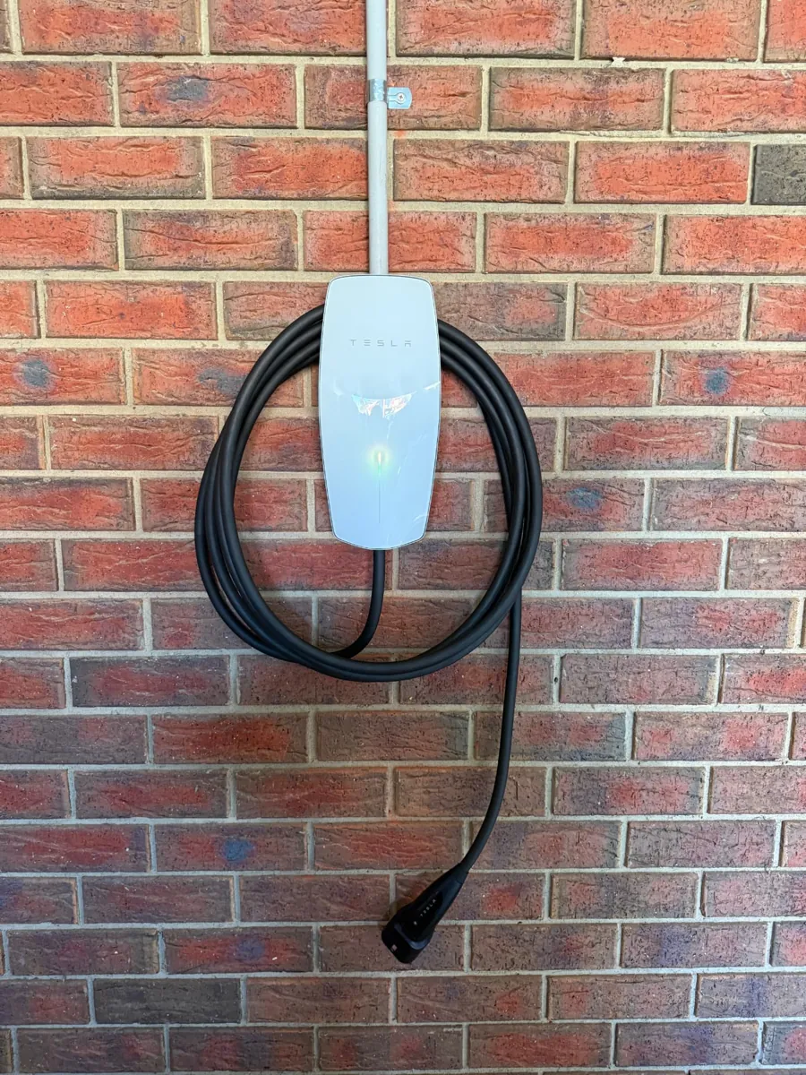 Tesla Wall Connector installed on a brick wall with coiled cable