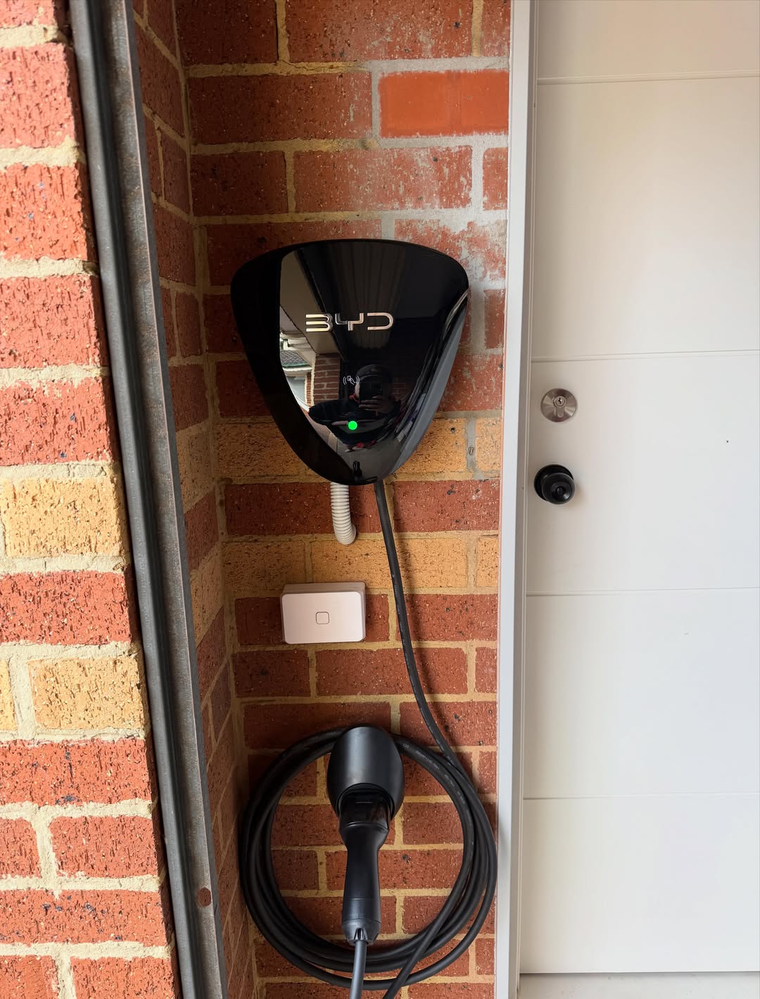 BYD home EV charger mounted on a brick wall with cable neatly coiled
